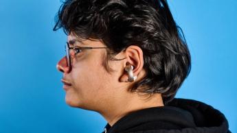 Soundcore AeroClip open-ear earbuds in champagne mist against a blue backdrop