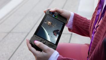 En person som håller i en svart handhållen PC-spelkonsol