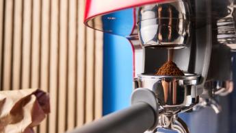 Una macchina da caffè espresso Smeg rossa con macinacaffè a macine, su sfondo blu