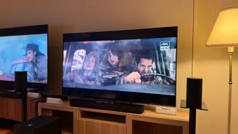 65-дюймовый телевизор Sony Bravia 5 на деревянной подставке, на экране — сцена из фильма «Охотники за привидениями: Ледяное царство»