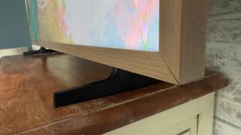 Hisense Canvas 55-inch TV on wooden furniture showing TV's feet and bottom right edge of wood-effect frame