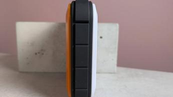 Vista lateral del RUGD Power Brick apoyado sobre un pedestal en un escritorio con fondo rosa