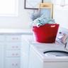 Lave-linge à chargement par le dessus blanc avec un panier rouge dans une buanderie