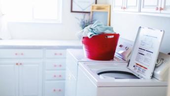 Lave-linge à chargement par le dessus blanc avec un panier rouge dans une buanderie