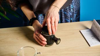 Uma pessoa rosqueando a tampa na cafeteira portátil Wacaco Picopresso