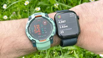 Nahaufnahme einer türkisfarbenen Garmin Instinct 3 Smartwatch am Handgelenk einer Person neben einer schwarzen Apple Watch Series 10 mit dunkelblauem Armband