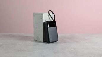 Batería externa INIU P51L-E1 sobre un pedestal en un escritorio con fondo rosa