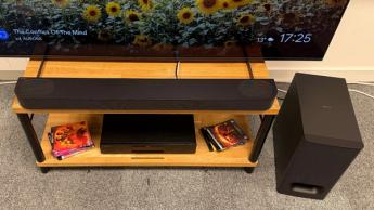 Sony Bravia Theatre Bar 6 soundbar on wooden AV rack with subwoofer to right below TV showing sunflowers