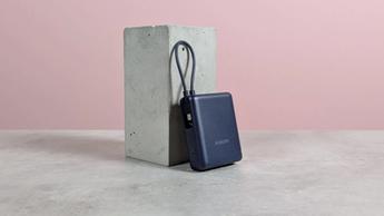Power bank Xiaomi de 33W y 10.000 mAh reposando sobre un pedestal en un escritorio con fondo rosa