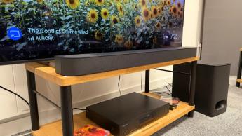 Sony Bravia Theatre Bar 6 soundbar on wooden AV rack underneath TV showing sunflowers on screen, with subwoofer sitting to the right