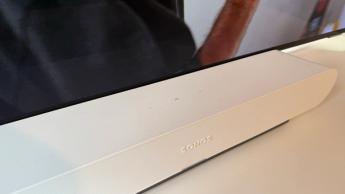 The Sonos Ray soundbar photographed on a white desk in front of a Philips OLED TV