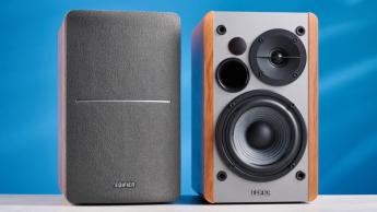 Die Edifier R1280T Regallautsprecher in Holzbraun vor blauem Hintergrund, mit Fokus auf Lautstärkeregler, Lautsprechertreiber, Hochtöner, RCA- und Aux-Eingänge sowie Fernbedienung