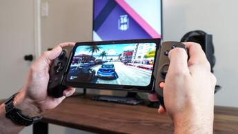 Person som spelar ett racingspel med Backbone Pro-kontrollen vid ett gamingbord