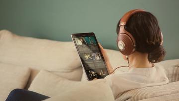 En kvinde iført Focal Stellia on-ear hovedtelefoner og holder en tablet, mens hun streamer musik på Qobuz
