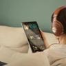En kvinde iført Focal Stellia on-ear hovedtelefoner og holder en tablet, mens hun streamer musik på Qobuz