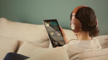 En kvinde iført Focal Stellia on-ear hovedtelefoner og holder en tablet, mens hun streamer musik på Qobuz