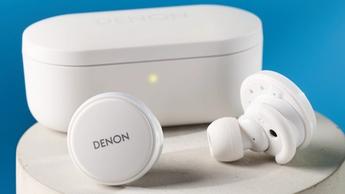 Weiße Denon perL Pro kabellose Ohrhörer mit runden Earbuds und passender weißer Ladebox auf blauem Hintergrund