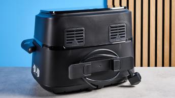 O compartimento para armazenar o cabo da fritadeira elétrica Philips FlexDrawer Série 1000 em destaque sobre um fundo azul