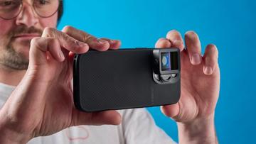 Uma pessoa segurando um iPhone 15 Pro equipado com uma lente Moment