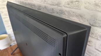 Смарт-телевизор TCL C6KS с диагональю 50 дюймов на фоне кирпичной стены, вид сверху и сзади