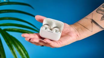 Soundcore AeroClip open-ear earbuds in champagne mist against a blue backdrop