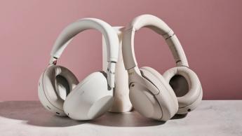 Sony WH-1000XM6 og WH-1000XM4 trådløse hovedtelefoner lænet op ad en cylindrisk stolpe