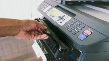 Hand som byter ut en tonerkassett i en topprankad laserskrivare