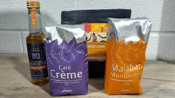 Sacchi di chicchi di caffè e una bottiglia di sciroppo accanto alla macchina da caffè Jura J10 durante i test del prodotto