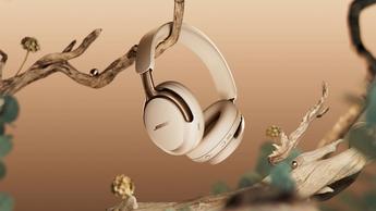 Fones de ouvido Bose QuietComfort Ultra na cor areia driftwood apoiados em um galho de árvore com pérolas ao redor