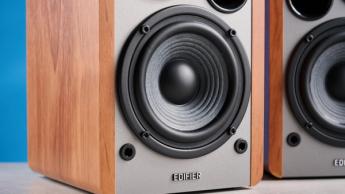 Edifier R1280T Regallautsprecher in Holzoptik auf blauem Hintergrund, mit Lautstärkereglern, Treibern, Hochtönern, RCA- und AUX-Eingängen sowie Fernbedienung