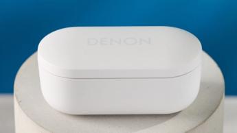 Denon perL Pro True-Wireless-Kopfhörer in Weiß mit rundem Design und passender weißer Ladehülle auf blauem Hintergrund