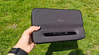 Портативный ультракороткофокусный проектор Optoma Photon Go в руке на зелёной лужайке