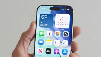 En person håller en iPhone som visar hemskärmen i iOS 26