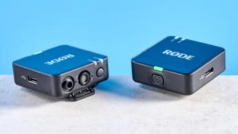 Das Rode Wireless GO Gen 3 Mikrofon-Set mit einem Empfänger, zwei Sendern und Zubehör wie Windschutz und Ladekabeln vor blauem Hintergrund