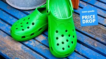 Un par de sandalias Crocs verdes sobre un piso de madera azul