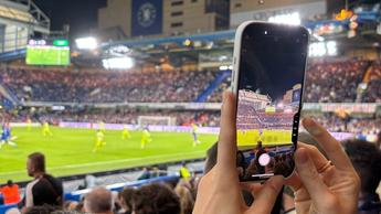 En person använder kamerakontrollerna på iPhone 16 Pro för att fånga action under en fotbollsmatch
