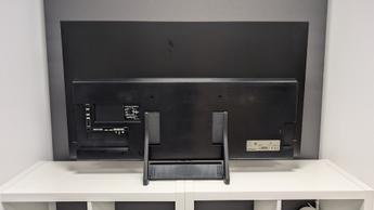 Вид сзади на 48-дюймовый OLED-телевизор Samsung S90F на белой деревянной мебели