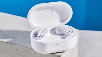 Ein Paar weiße AKG N5 Hybrid-Ohrhörer von Harman in ihrem Ladeetui mit Zubehör