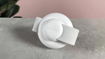 En kompakt Anker-opladningsstation står oprejst med Anker-logoet synligt på fronten, ved siden af opladningsmodulet til uret