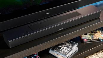 Die schwarze Bose Smart Soundbar 2024 mit Fernbedienung, ausgestattet mit zwei Touch-Bedienelementen und einer Netzabdeckung