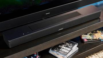 Die schwarze Bose Smart Soundbar 2024 mit Fernbedienung, ausgestattet mit zwei Touch-Bedienelementen und einer Netzabdeckung