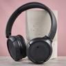JBL Tune 510BT ワイヤレスヘッドホンがピンクの背景にある柱にもたれかかっている