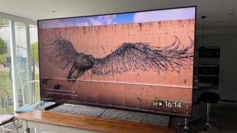 Телевизор TCL 98C7K с диагональю 98 дюймов на обеденном столе, на экране — граффити с хищной птицей