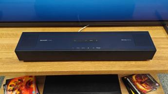 Саундбар Sharp HT-SB700 с Dolby Atmos на AV-стойке под телевизором и коллекцией Blu-ray дисков