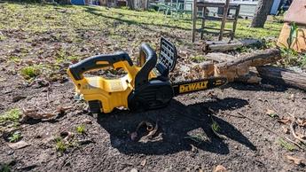Tronçonneuse à batterie DeWalt 20V MAX XR de 12 pouces posée sur l'herbe dans un jardin