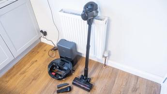 Eufy E20 robovac in dock, with manual vacuum and other accessories next to it