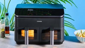 Uma fritadeira elétrica Cosori preta com duas cestas transparentes, luzes de LED, uma grade para cozimento e espetos para churrasco