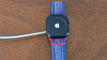 Primeiro plano da instalação do watchOS 26 num Apple Watch Series 10 com um iPhone 12 Mini