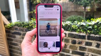 Eine Person hält ein iPhone, auf dem die Fitbit Premium-Funktionen in der Fitbit-App angezeigt werden