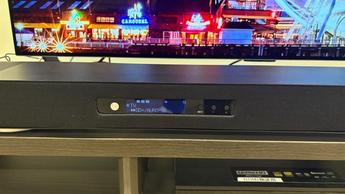 Акустическая система Yamaha True X Surround 90A с беспроводными тыловыми динамиками и сабвуфером установлена в минималистичной комнате с плоским телевизором.